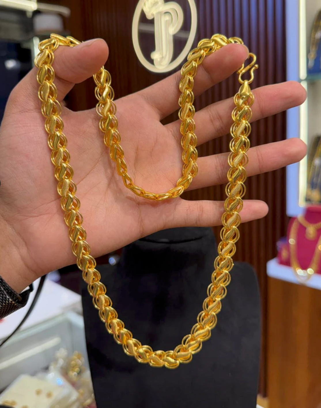 Gold chain held by a hand with a blurred background