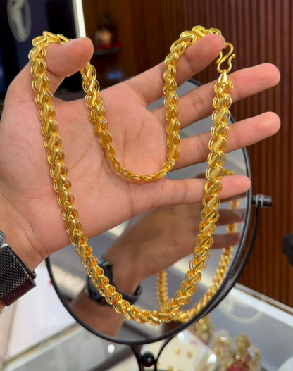 Gold chain held by a hand with a blurred background