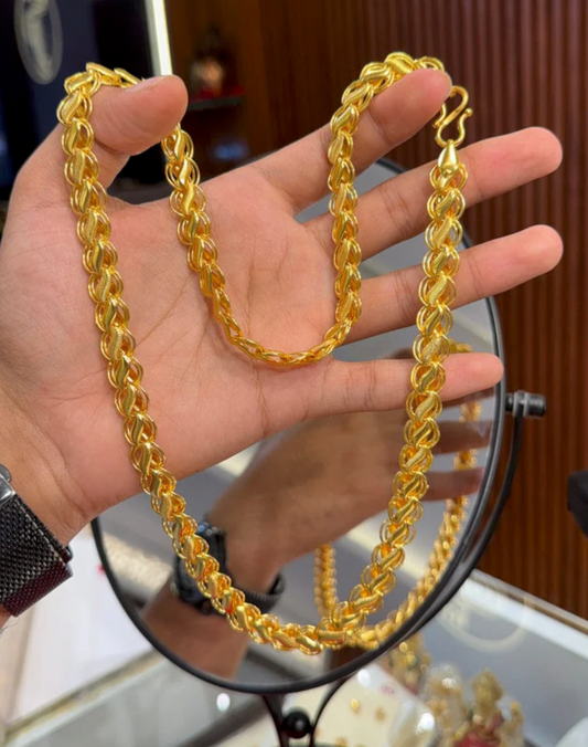 Gold chain held by a hand with a blurred background