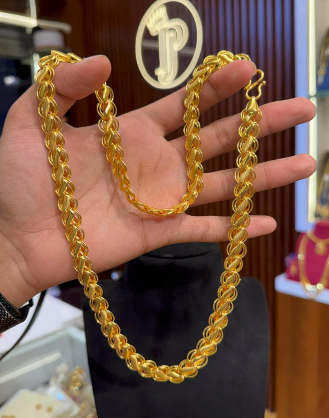 Gold chain held in a hand with a blurred background