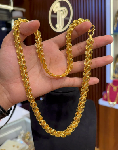 Gold chain held in a hand with a blurred background